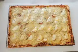 Pizza carrée généreusement garnie de fromages fondants, une spécialité artisanale du camion pizza événementiel PIZZ'A YANN. 
