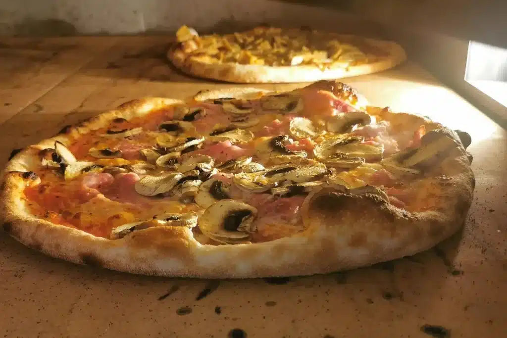 Pizza aux champignons et jambon cuite au four, prête à être dégustée lors d’un événement en Aveyron.