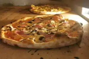 Pizza aux champignons et jambon cuite au four, prête à être dégustée lors d’un événement en Aveyron.
