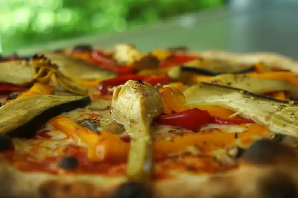 Gros plan sur une pizza aux légumes grillés avec artichauts, poivrons et aubergines, préparée par le camion pizza événementiel PIZZ'A YANN. ​​