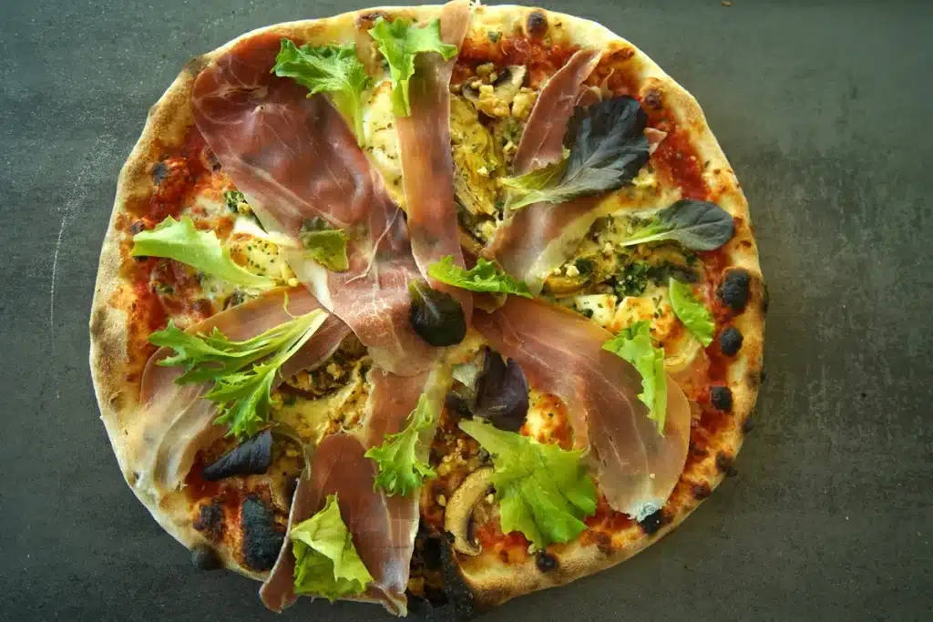 Pizza gourmande au jambon cru, garnie de salade verte et de mozzarella, cuite dans le food truck pizza PIZZ'A YANN en Aveyron.