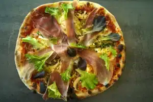 Pizza gourmande au jambon cru, garnie de salade verte et de mozzarella, cuite dans le food truck pizza PIZZ'A YANN en Aveyron.

