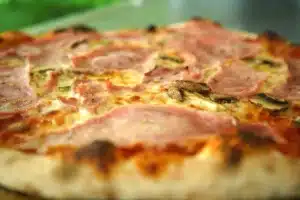 Pizza savoureuse au jambon et champignons, sortie du four du food truck pizza PIZZ'A YANN, avec une pâte croustillante et dorée. ​​







